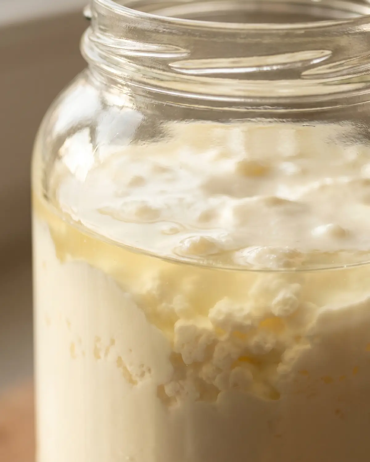 quark fermentiert Nahaufnahme eines Kefirglases mit klarer Trennlinie zwischen Molke und cremiger fermentierter Milch.